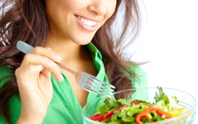 笑顔でサラダを食べる女性の画像